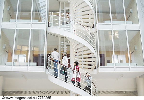 Business people climbing spiral staircase in office