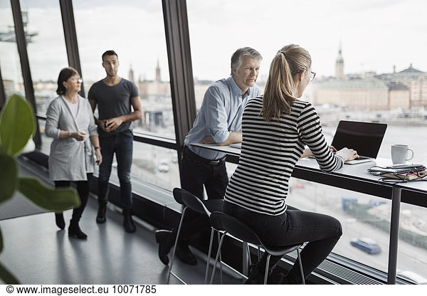 Business people discussing by window in office