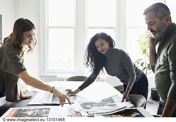 Business people discussing over photograph printouts in conference room