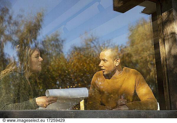 Business people discussing paperwork at sunny cafe window