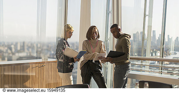 Business people discussing paperwork in sunny urban office