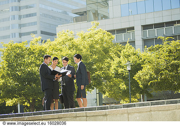 Business people discussing paperwork outdoors