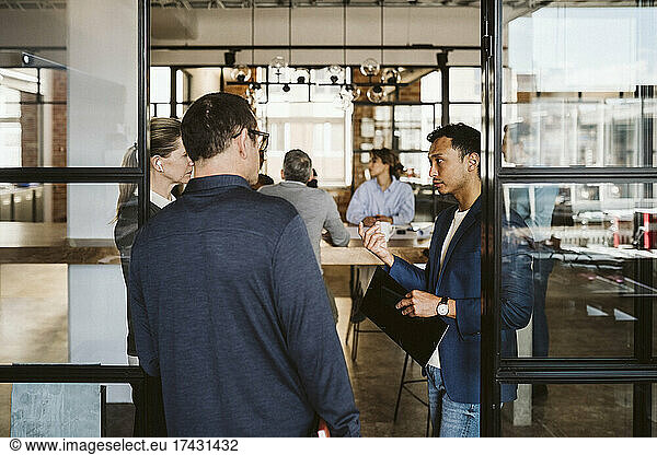 Business people discussing while standing at doorway