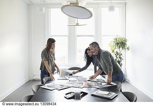Business people examining photograph printouts in conference room