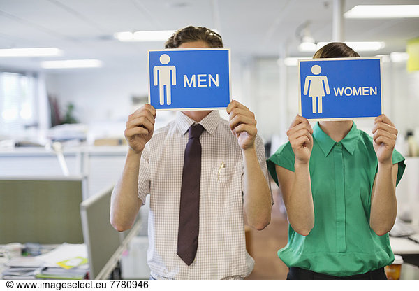 Business people holding ‘men’ and ‘women’ signs