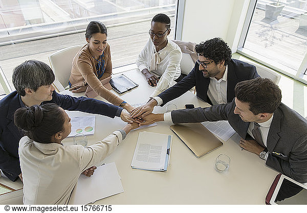 Business people joining hands in conference room meeting