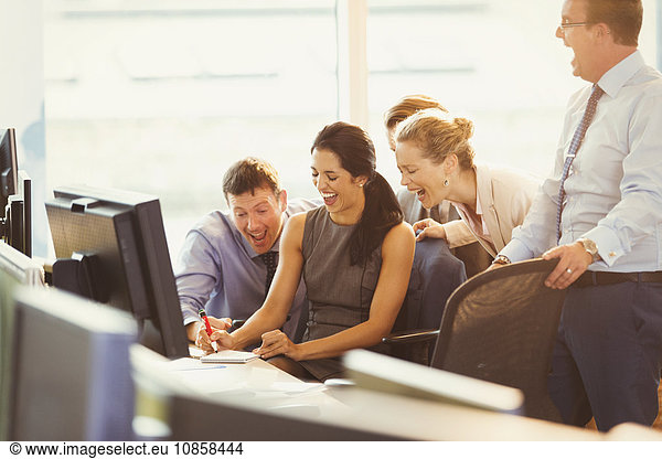Business people laughing at desk in office