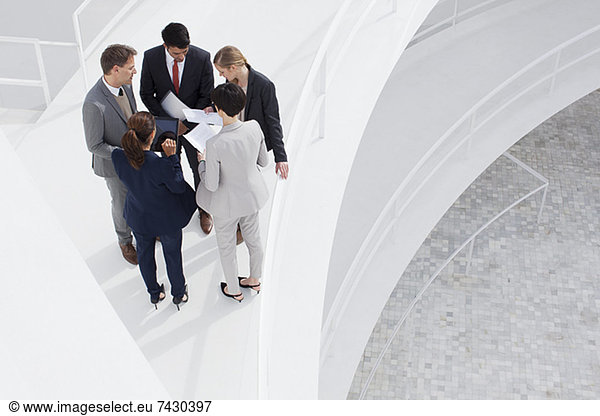 Business people reviewing paperwork on elevated walkway