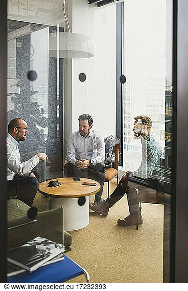Business people seen through door while discussing with each other at office