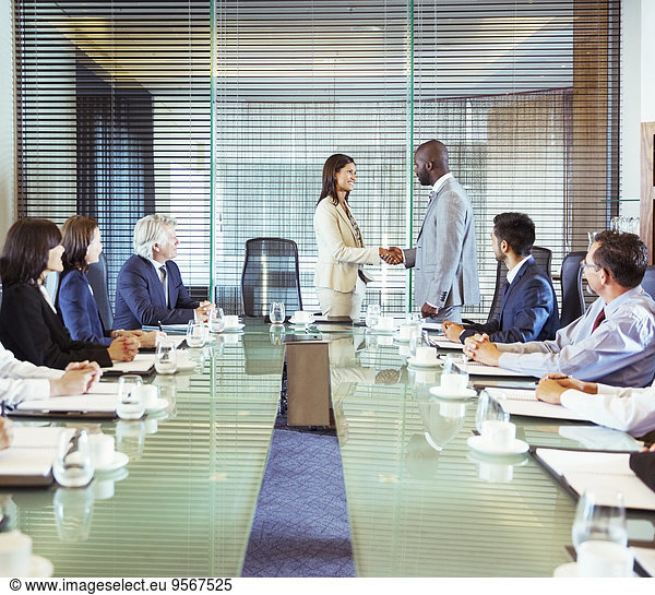 Business people shaking hands in conference room during business meeting