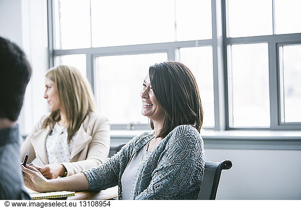 Business people smiling while sitting in meeting at board room