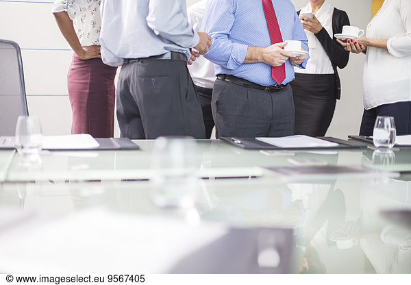 Business people standing in conference room with coffee cups in hands