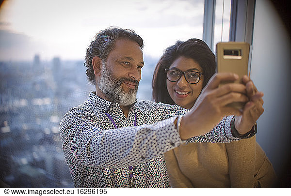 Business people taking selfie at highrise office window