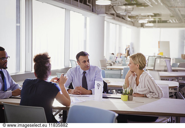 Business people talking at table in shared workspace