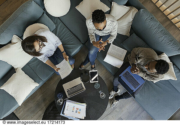 Business people with laptops and paperwork meeting on office sofa