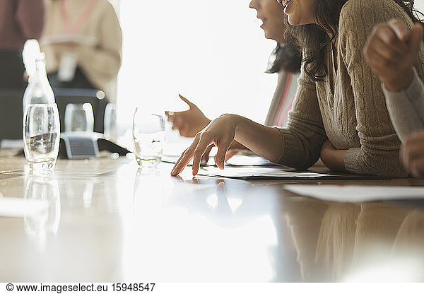 Business people with paperwork in sunny conference room meeting