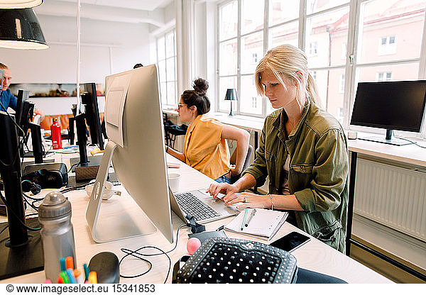 Business professionals working while sitting at desk in office
