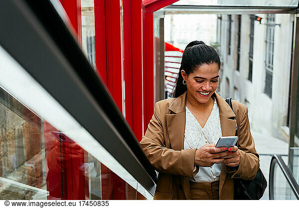Business woman checking her cellphone on an escalator