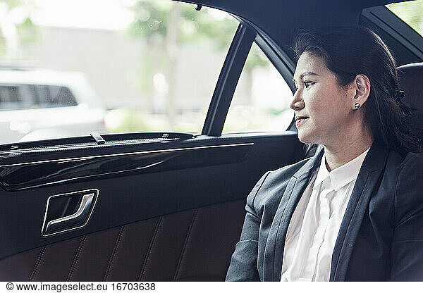 business woman looking out the window on backseat of her luxury car