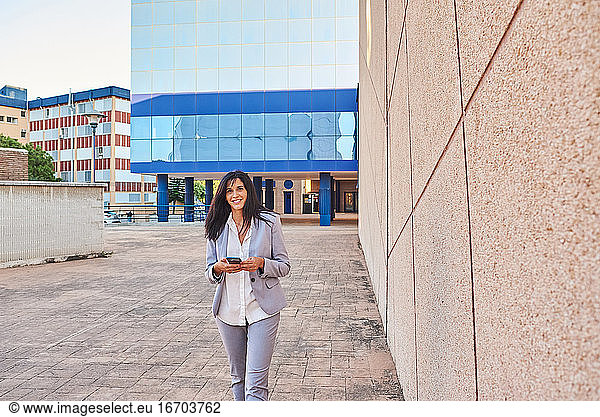 Business woman walking with mobile phone in hand.