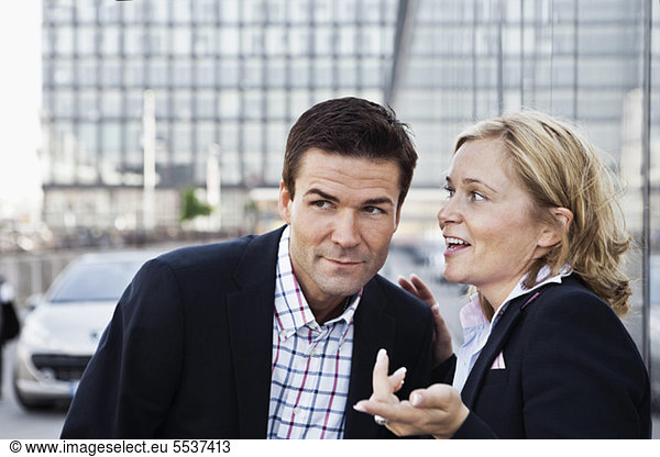 Business woman whispering something in businessman's ear