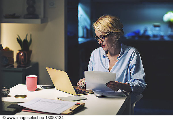 Business woman with document using laptop computer while working at home