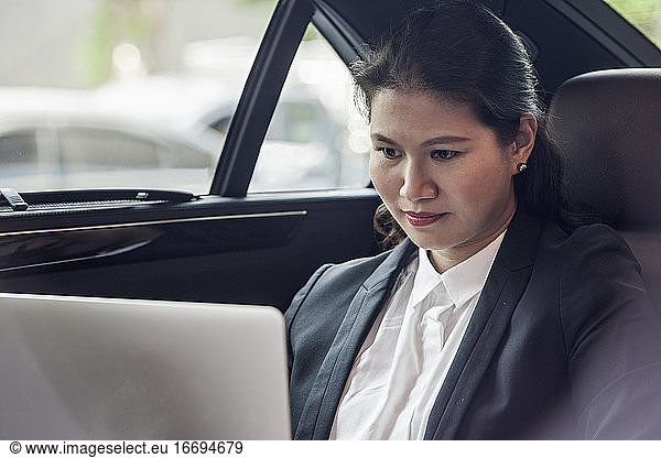 business woman working on the backseat of her luxury car
