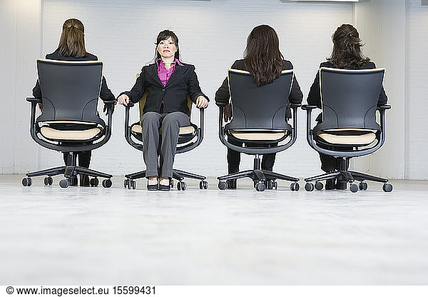 Business women sitting on office chairs.