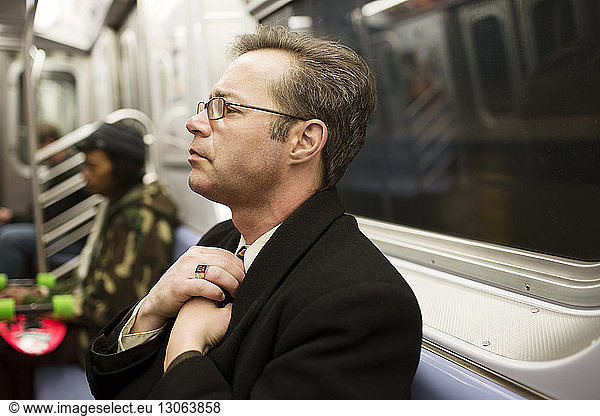 Businessman adjusting necktie in train