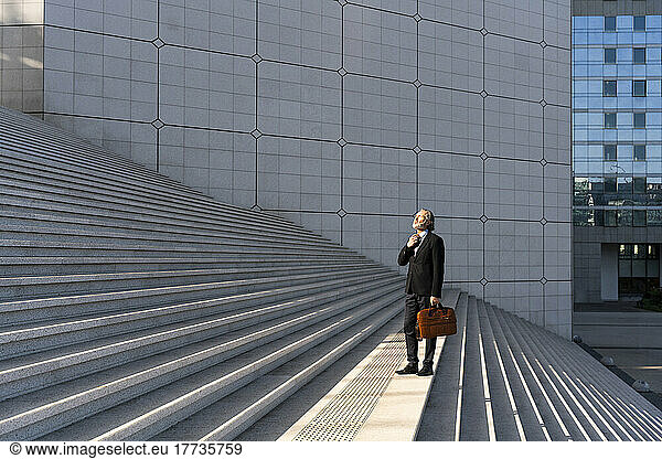 Businessman adjusting tie standing on staircase