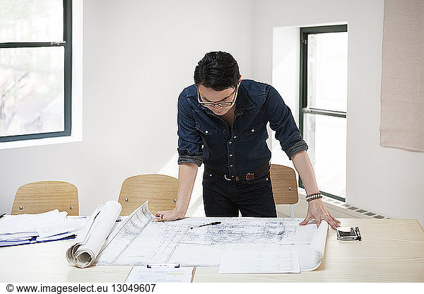 Businessman analyzing blueprint at desk in creative office