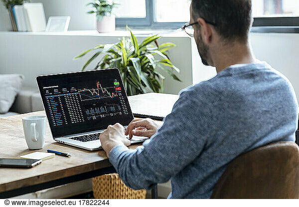 Businessman analyzing stock data on laptop at home
