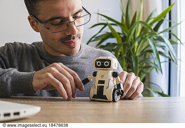 Businessman analyzing toy robot on desk in office