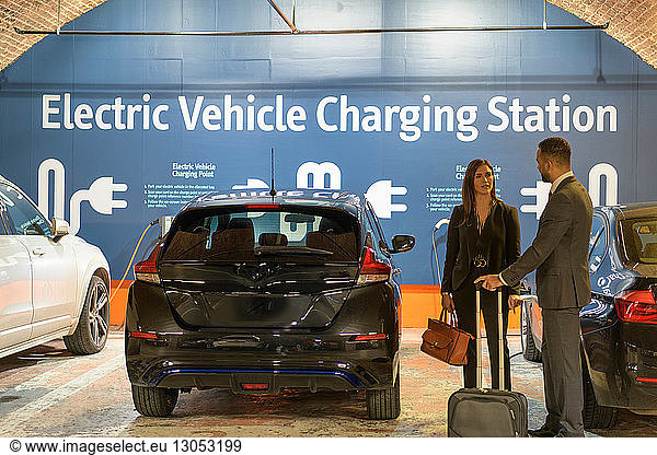 Businessman and businesswoman at electric vehicle charging station  Manchester  UK