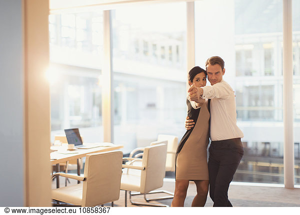 Businessman and businesswoman dancing in conference room