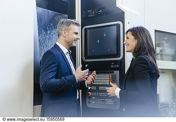 Businessman and businesswoman having a work meeting at a screen in a factory