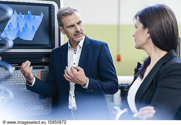 Businessman and businesswoman having a work meeting at a screen in a factory