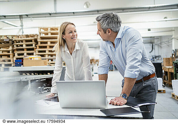 Businessman and businesswoman looking at each other discussing in factory