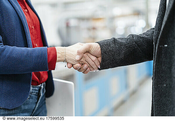 Businessman and businesswoman shaking hands at factory