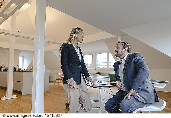 Businessman and businesswoman talking at table tennis table in office
