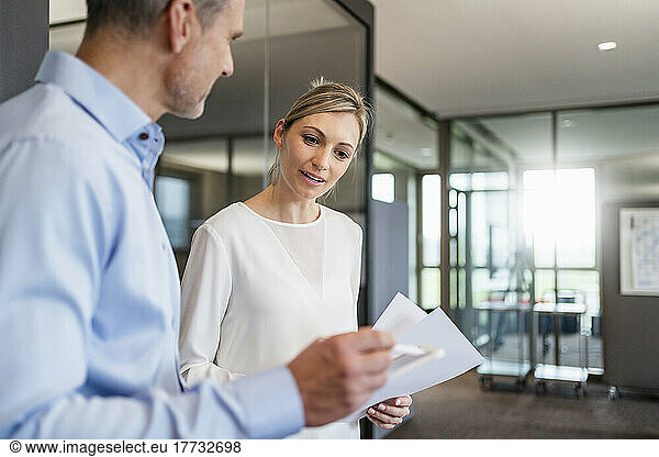 Businessman and businesswoman with digital tablet and documents talking in office