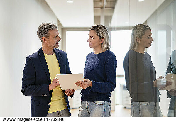 Businessman and businesswoman with digital tablet talking in office