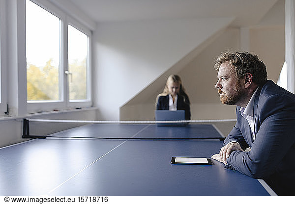 Businessman and businesswoman working at table tennis table in office