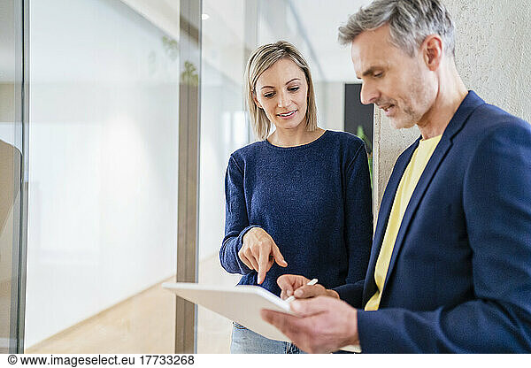 Businessman and businesswoman working together on digital tablet in office