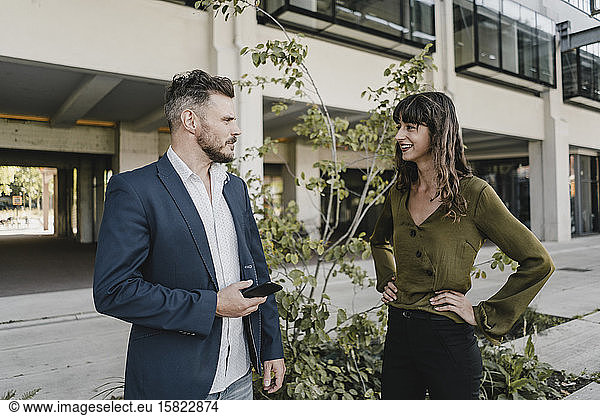 Businessman and casual businesswoman talking outdoors