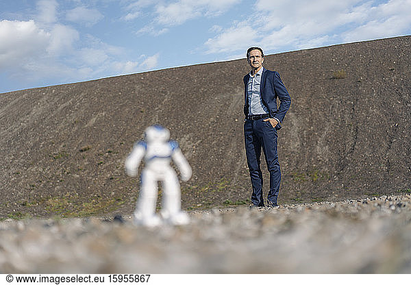 Businessman and miniature robot on a disused mine tip