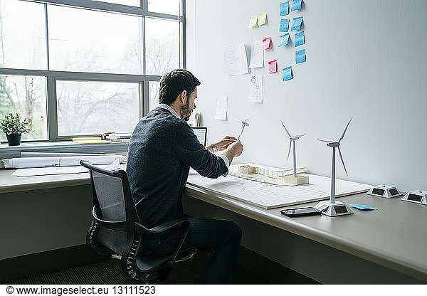 Businessman arranging wind turbine models on desk