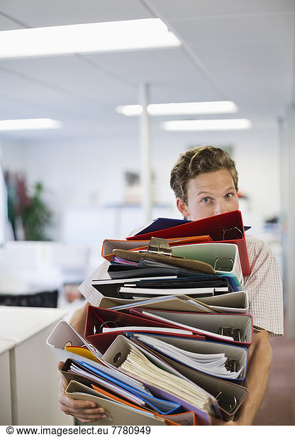 Businessman balancing folders in office