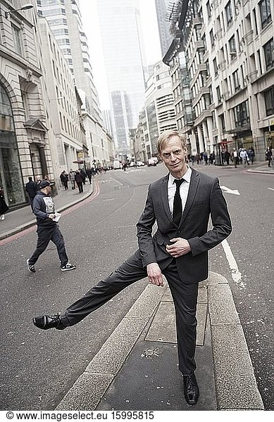 Businessman balancing on one leg at street in London  UK.