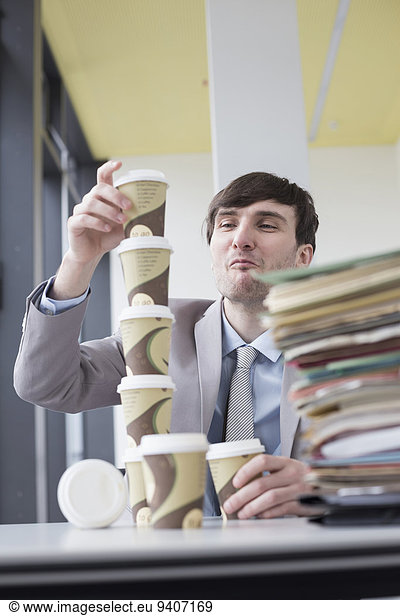 Businessman building tower with coffee cups  smiling